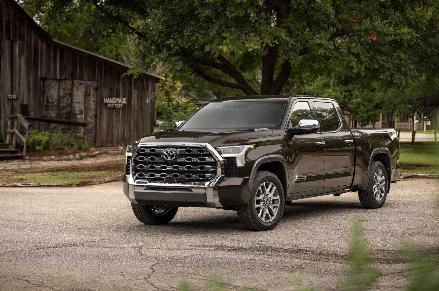 2025 Toyota Tundra - a dark brown 1794 Edition parked in front of a rustic building - AutoPark Barrie - Pre-owned car dealership in Innisfil, Ontario
