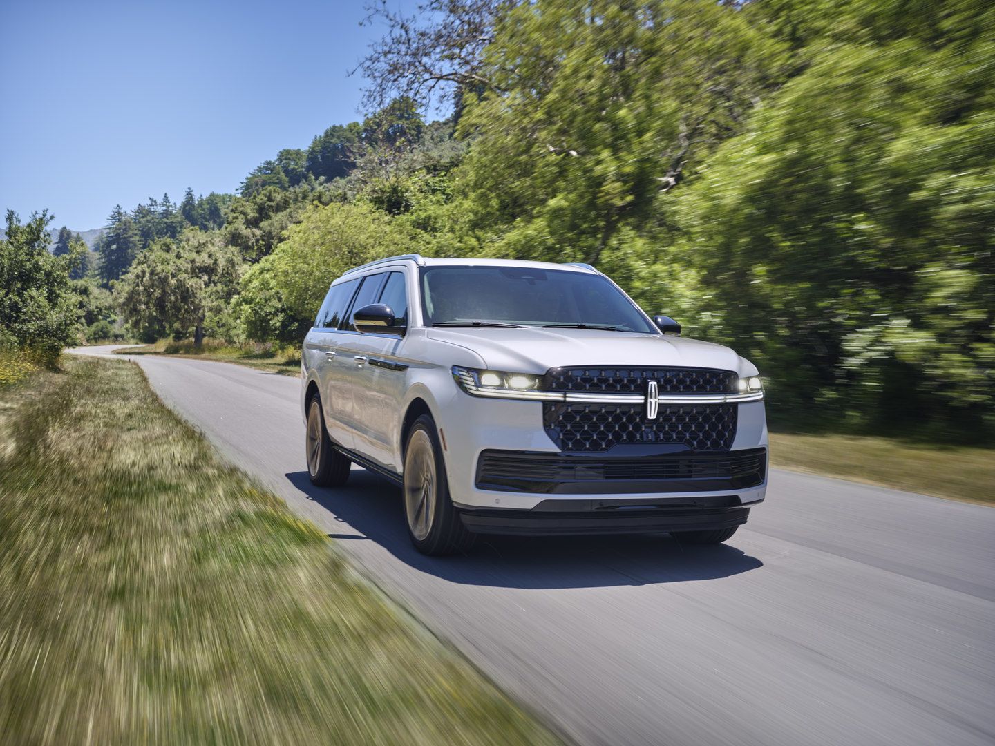 2025 Lincoln Navigator - A white 2025 Lincoln Navigator driving on a winding country road - Bayfield Lincoln - New car dealership in Barrie, Ontario