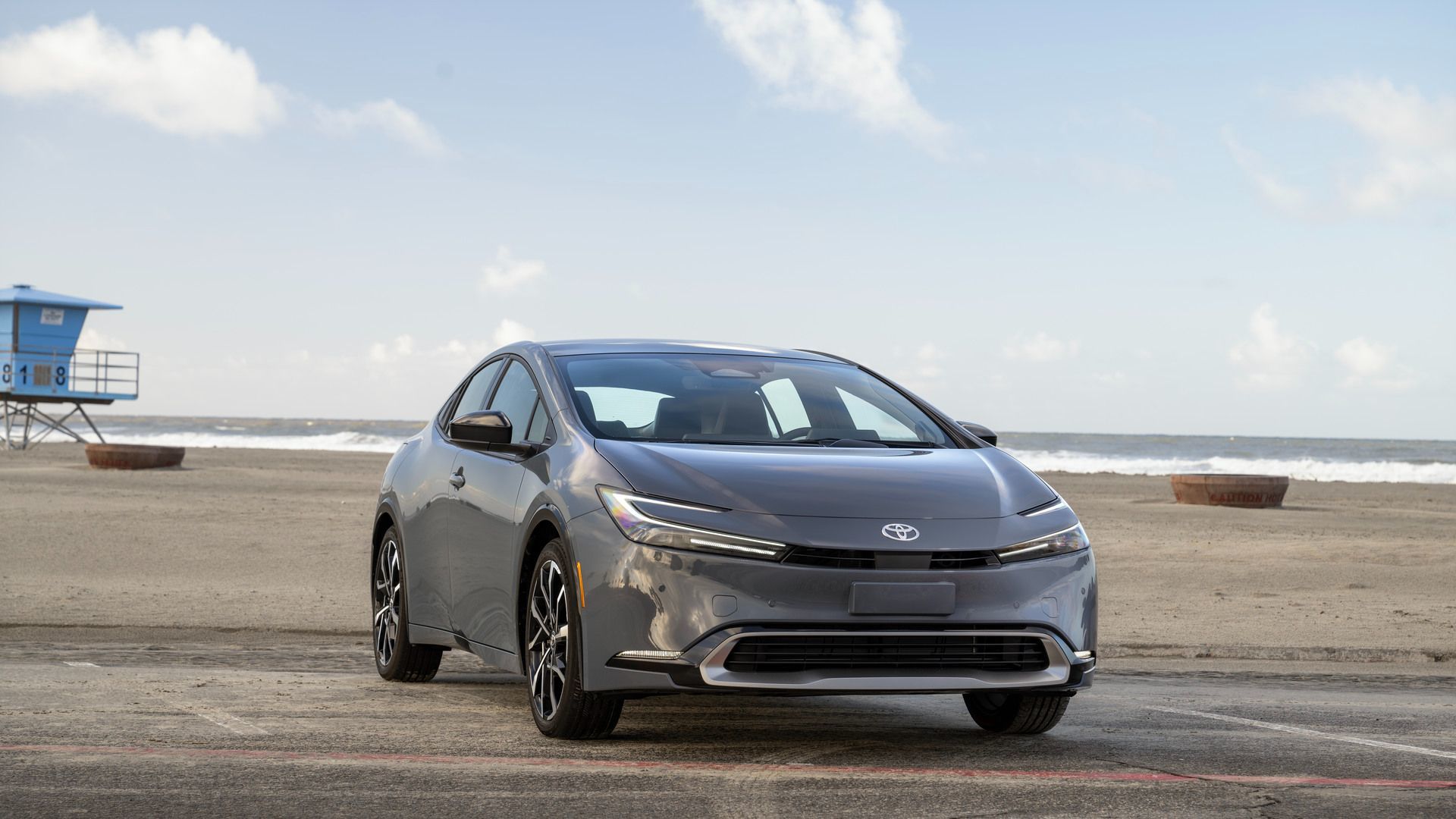 2026 Toyota Prius Prime - Front view of a grey 2026 Toyota Prius Prime parked on pavement at the beach - Oakville Toyota - New car dealership in Oakville, Ontario