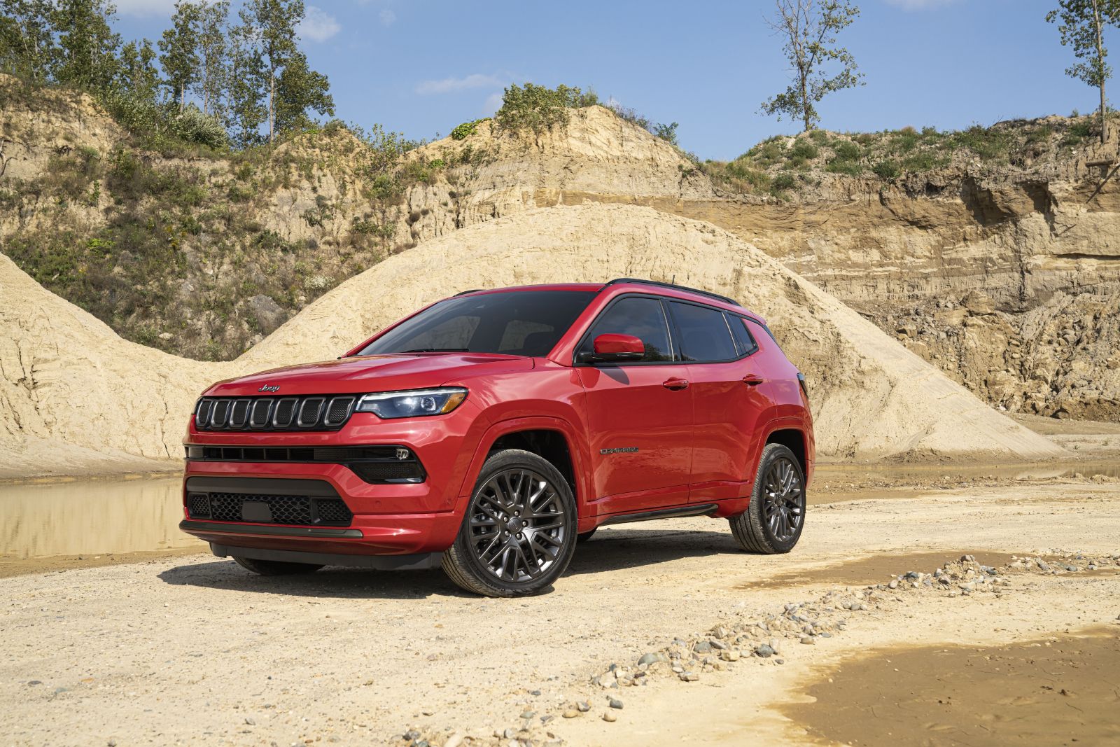 2026 Jeep Compass - a red Jeep Compass parked on sandy terrain in front of dirt mounds - Cooksville Chrysler Jeep Dodge Ram - New car dealership in Mississauga, Ontario