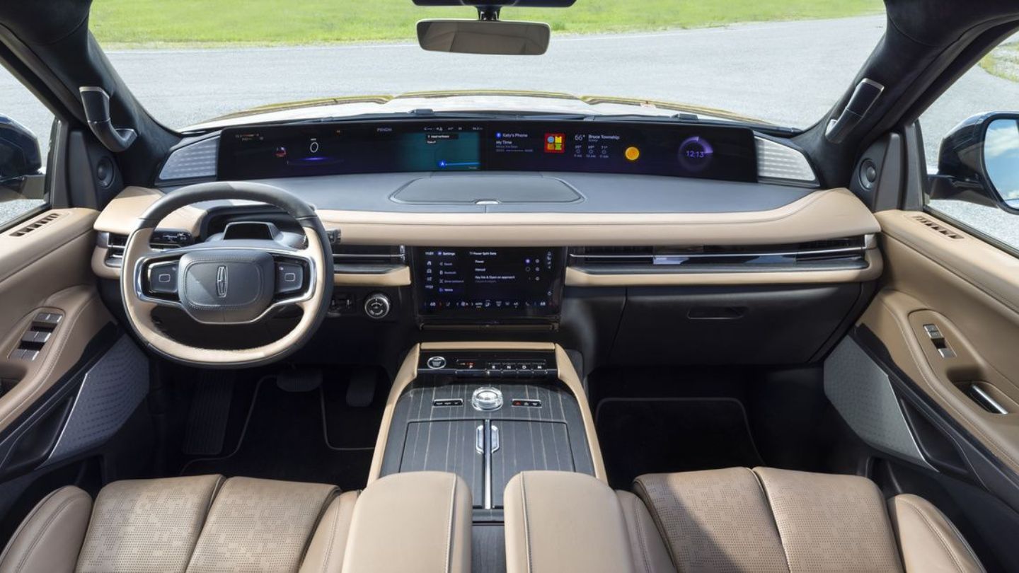 2026 Lincoln Navigator - front view of a white SUV driving on a paved road lined with green trees - Mayfield Lincoln - New car dealership in Brampton, Ontario