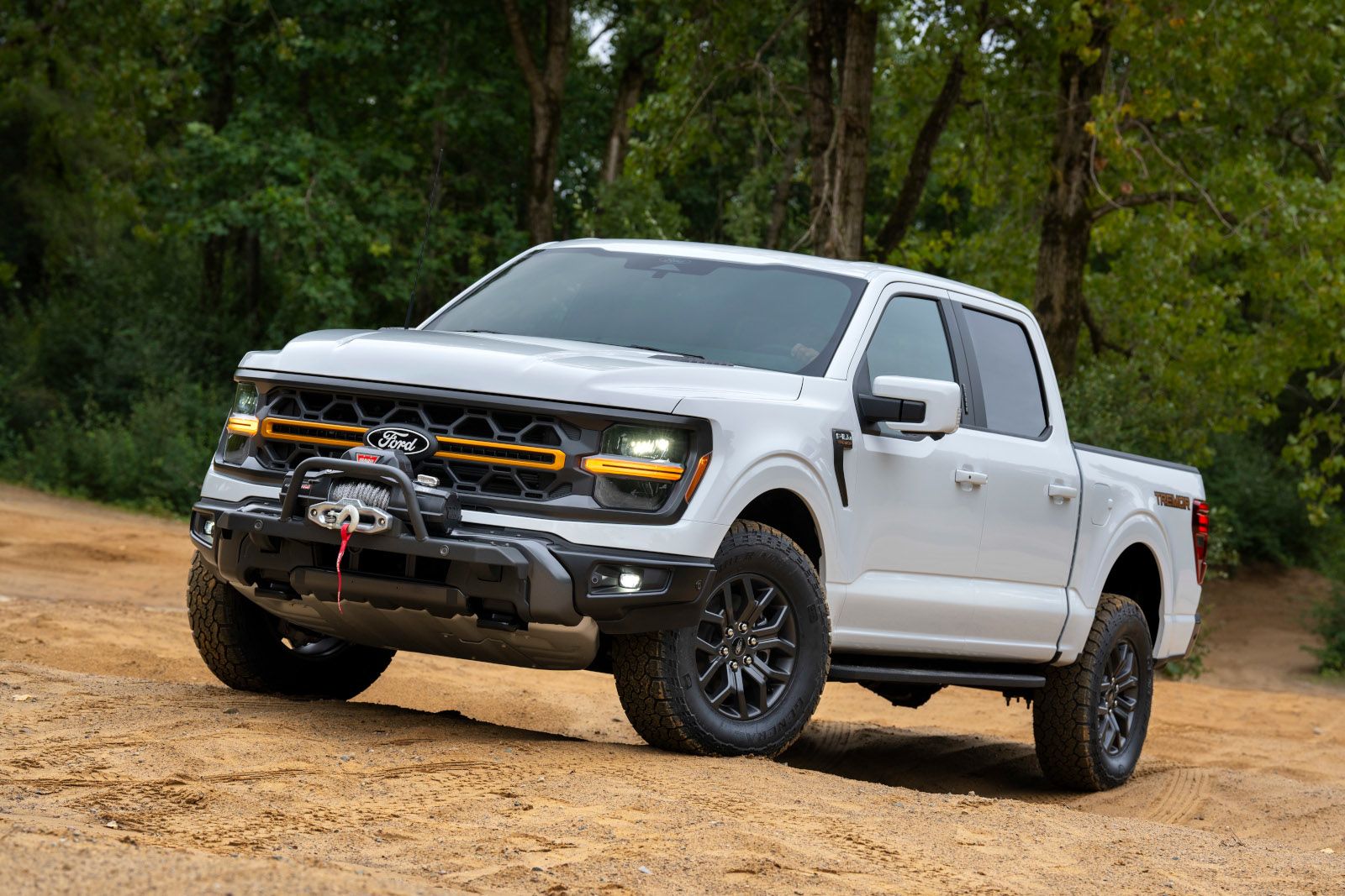2026 Ford F-150 Tremor - Front three-quarter view of a white 2026 Ford F-150 Tremor with a front-mounted winch parked on a dirt path - Bayfield Ford - New car dealership in Barrie, Ontario