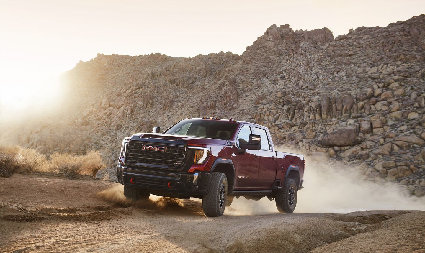 2026 GMC Sierra 2500 HD AT4X - a red GMC Sierra 2500 HD AT4X kicking up dust on an off-road desert trail - City Chevrolet, Buick, GMC - GMC car dealership in Toronto, Ontario