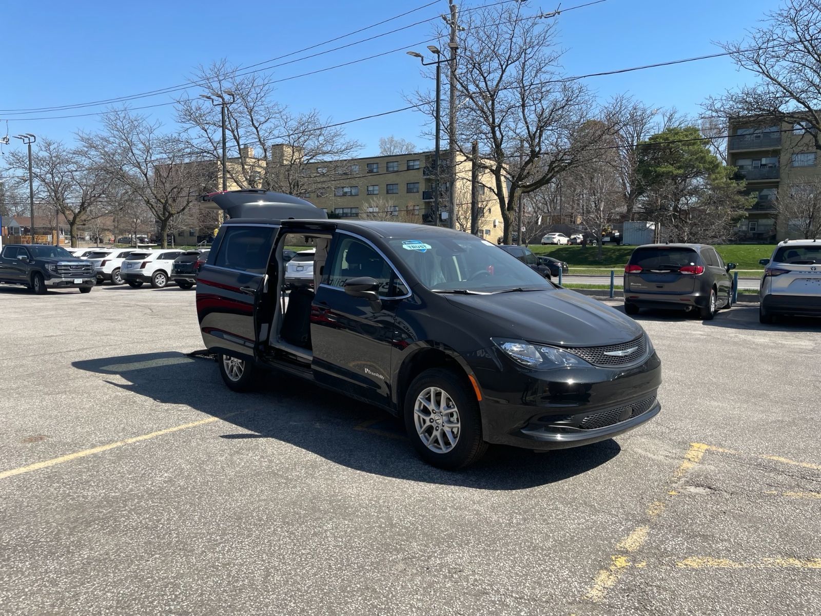 2026 Chrysler Grand Caravan - exterior side view of a black wheelchair accessible minivan with the side door and rear hatch open in a parking lot - Courtland Mobility - Accessible car dealership in Burlington, Ontario