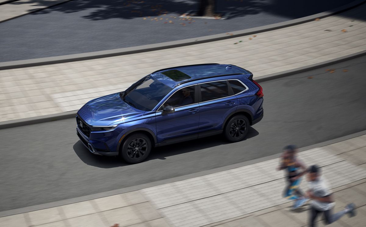 2026 Honda CR-V - elevated view of a blue 2026 Honda CR-V Sport Touring driving on a city street - Goderich Honda - New car dealership in Goderich, Ontario