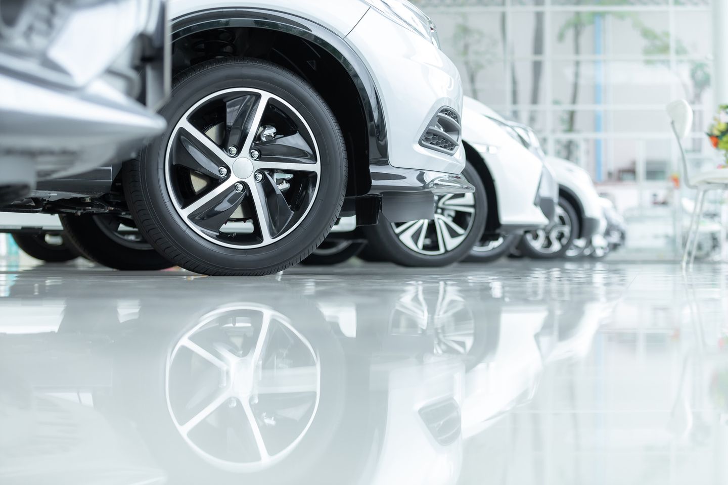 Used Cars - close-up of clean wheels and tires on a row of vehicles in a bright showroom - AutoPark Brampton - Used car dealership in Brampton, Ontario