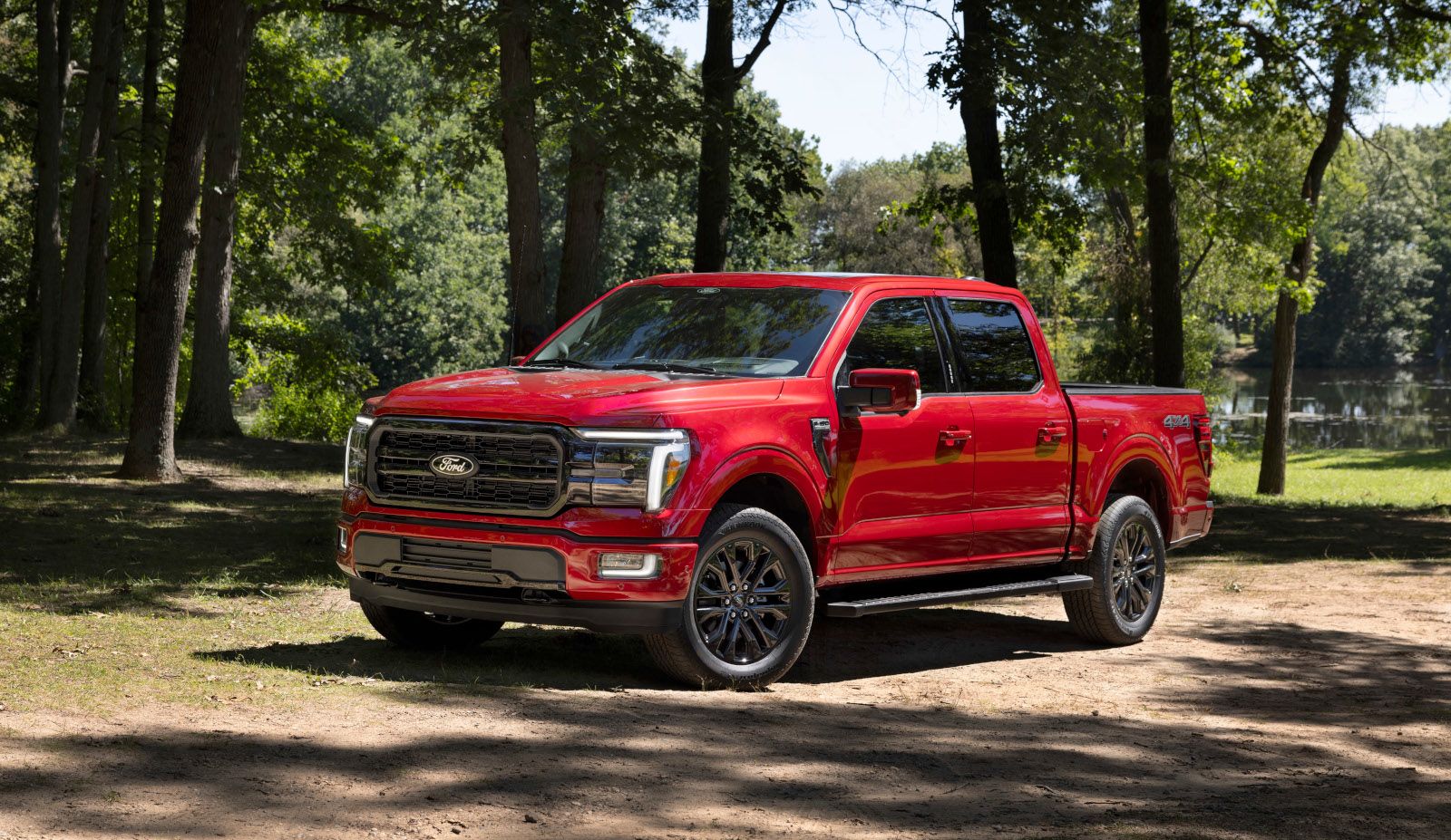 2026 Ford F-150 Lariat - front three-quarter view of a red pickup truck parked in a wooded area - Mayfield Ford - New car dealership in Brampton, Ontario