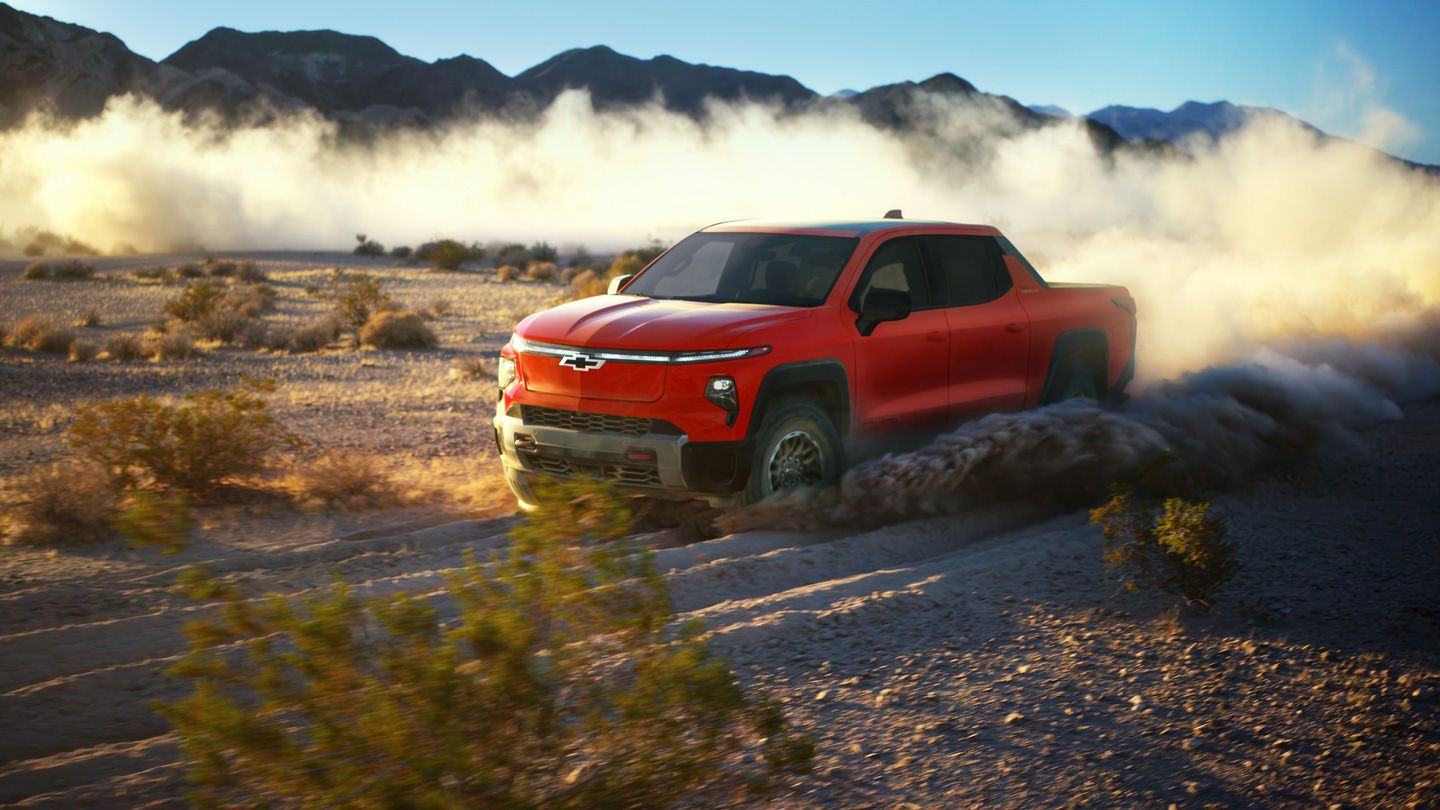 2026 Chevrolet Silverado EV Trail Boss - Front driver side view of a red 2026 Chevrolet Silverado EV Trail Boss kicking up a cloud of dust while driving off-road through a desert trail - Humberview Chevrolet, Buick, GMC - New car dealership in Toronto, On