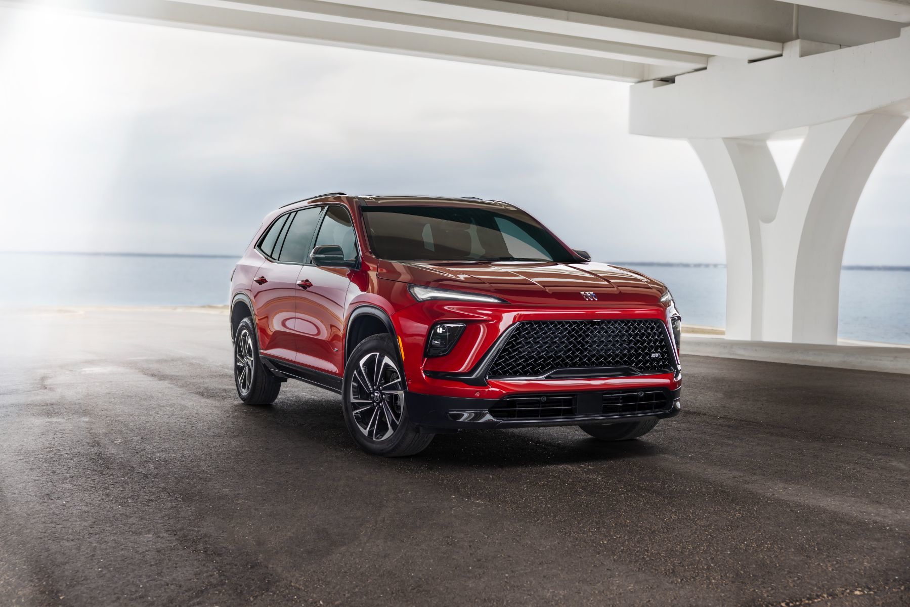 2026 Buick Enclave - front three-quarter view of a red 2026 Buick Enclave parked under a concrete bridge - Applewood Chevrolet, Buick, GMC - Buick new car dealership in Mississauga, Ontario