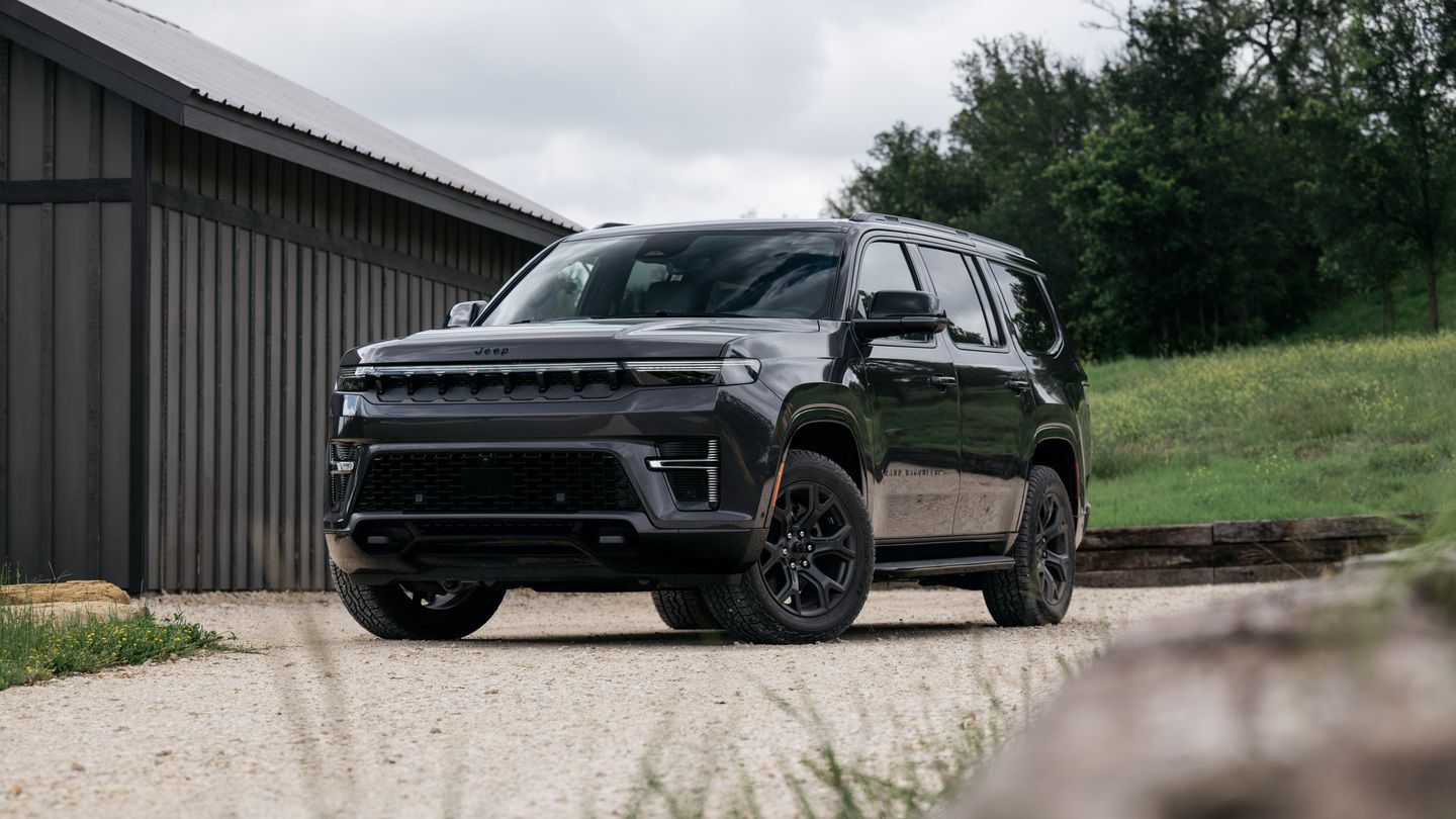 2026 Jeep Grand Wagoneer - a dark grey 2026 Jeep Grand Wagoneer parked on a gravel path next to a barn - Humberview Group - New car dealerships in Ontario
