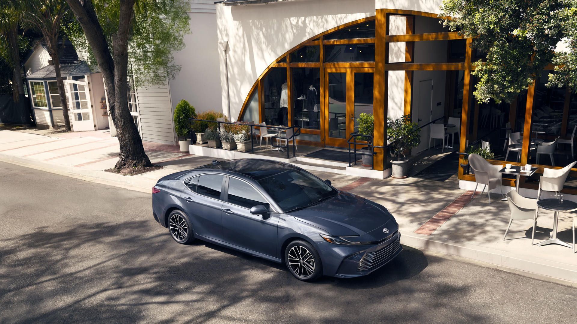 Toyota Camry - high-angle view of a grey Toyota Camry parked on a street in front of a cafe with outdoor seating - Oakville Toyota - Toyota car dealership in Oakville, Ontario