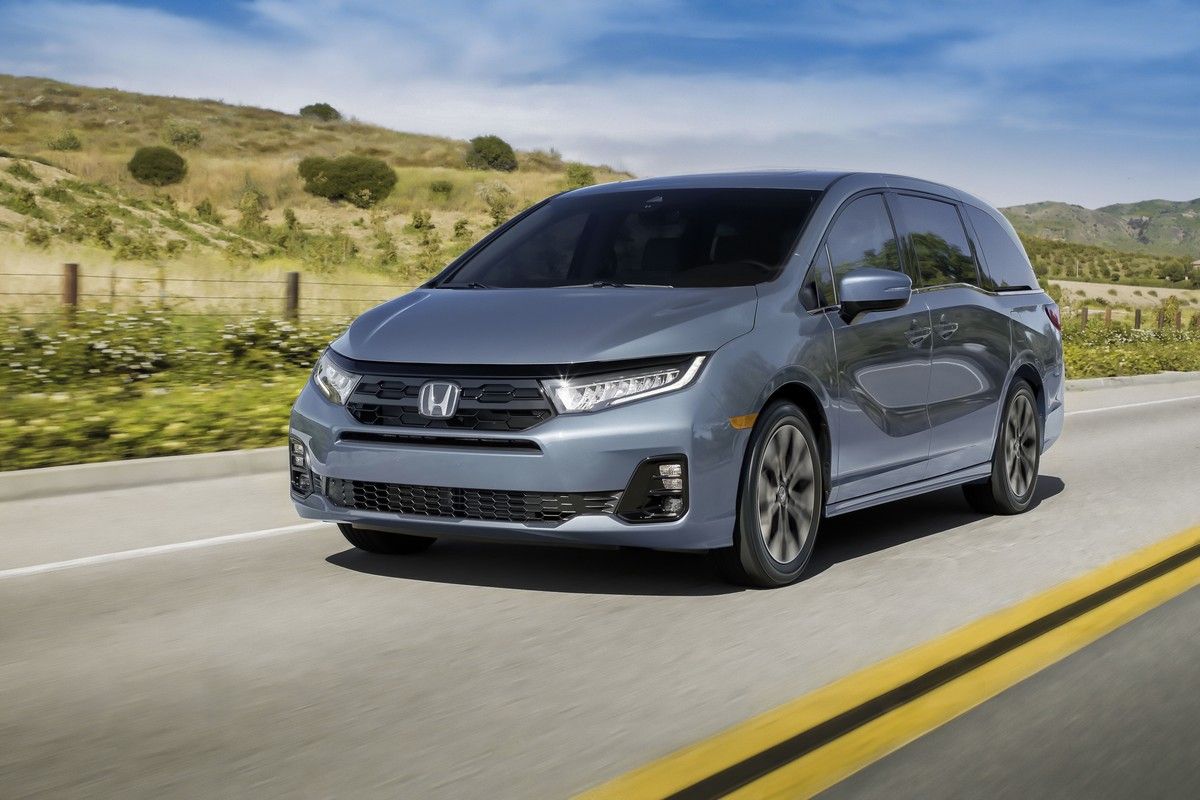 2027 Honda Odyssey - front three-quarter view of a 2027 Honda Odyssey driving on an open road - Orangeville Honda - Honda new car dealership in Orangeville, Ontario