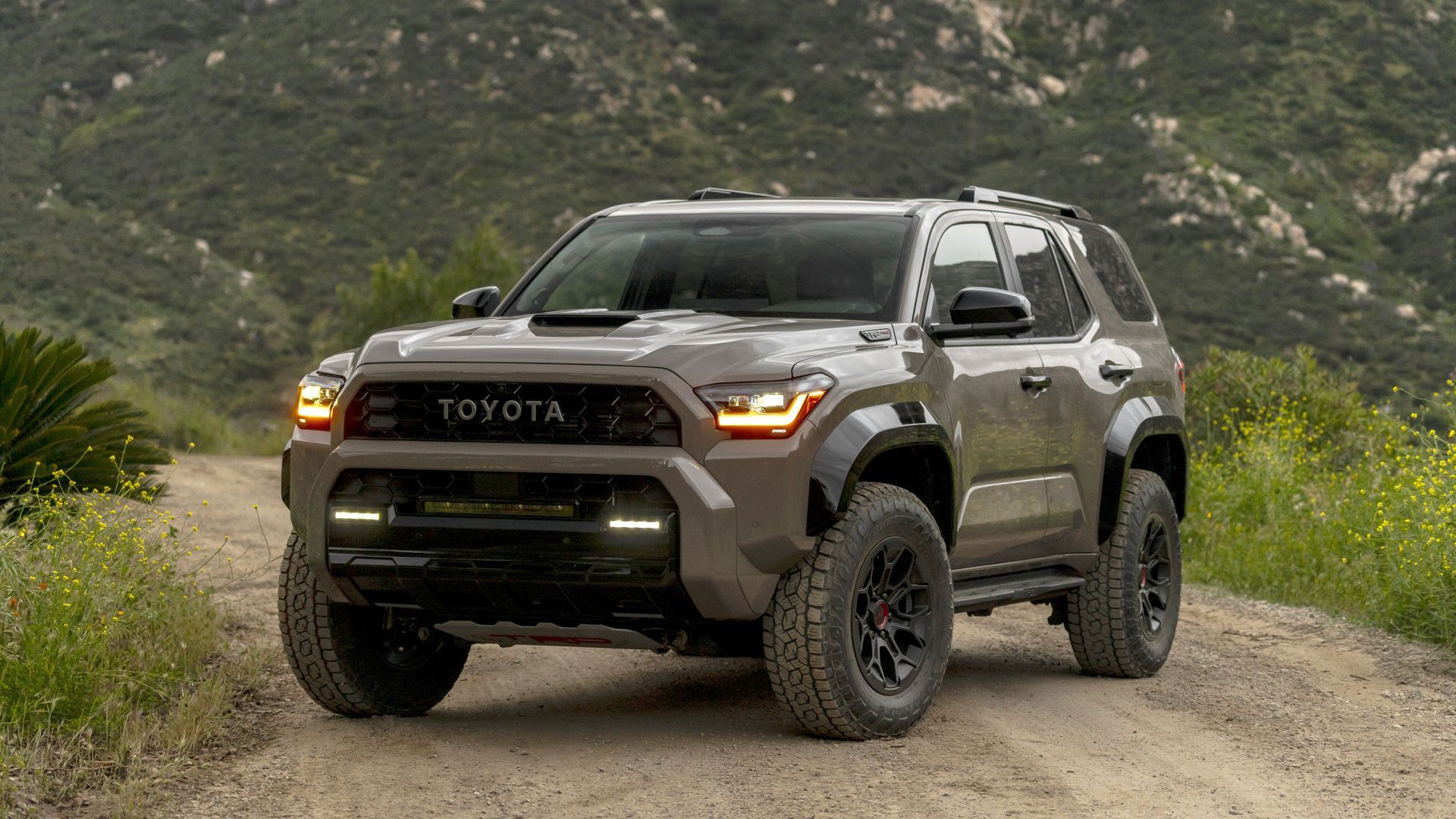 2027 Toyota 4Runner - front three-quarter view of an earth-toned Toyota 4Runner TRD Pro on an off-road mountain trail - Oakville Toyota - Toyota new car dealership in Oakville, Ontario