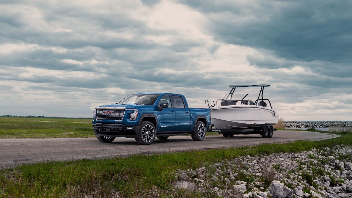 2027 GMC Sierra Denali - blue 2027 GMC Sierra Denali towing a boat on a coastal road - Humberview Group - New car dealerships in Ontario