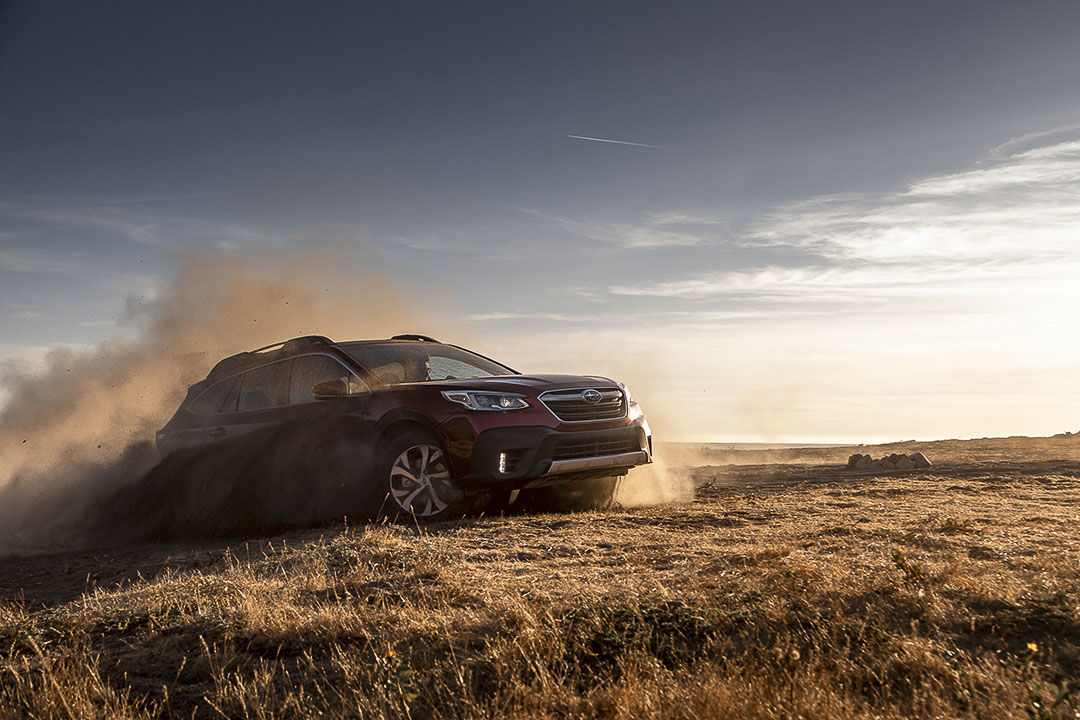 Subaru Outback Limited 2022 entouré de poussière dans un champ