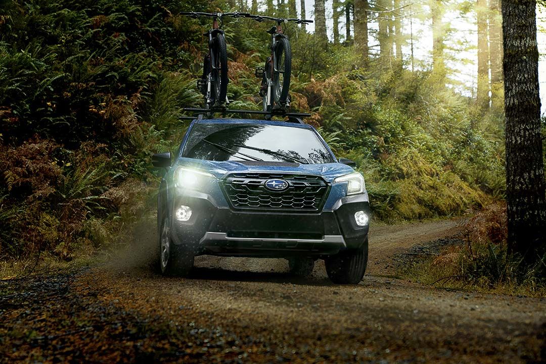 Vue avant d'un Subaru Forester Wilderness 2022 roulant sur un chemin de terre en nature