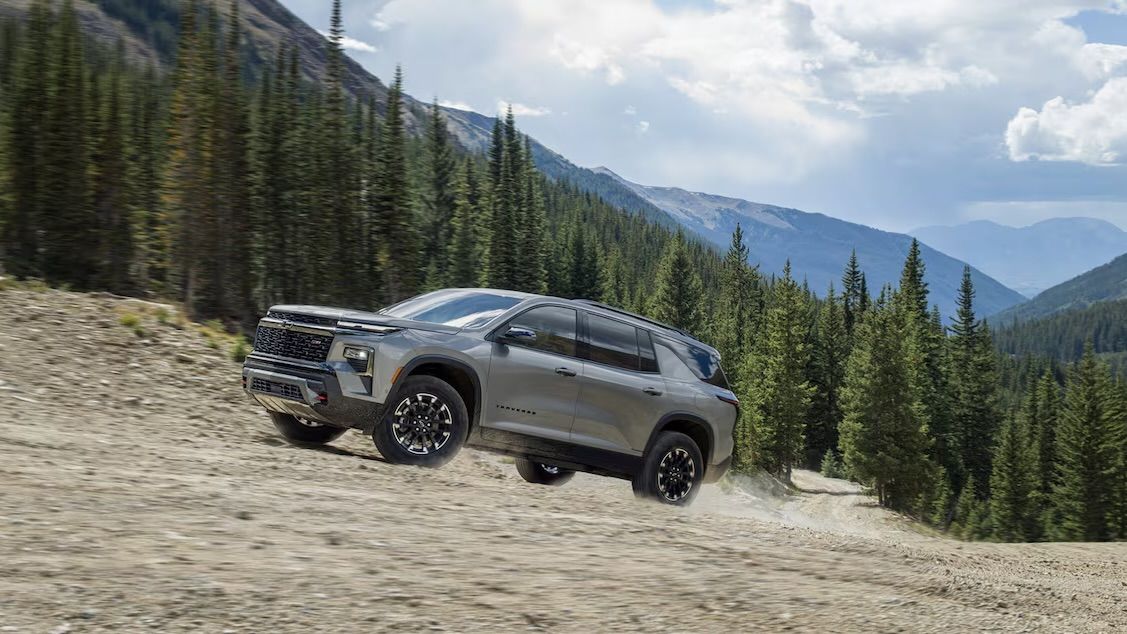 Le Chevrolet Traverse qui monte un chemin de gravel au milieu des sapins.