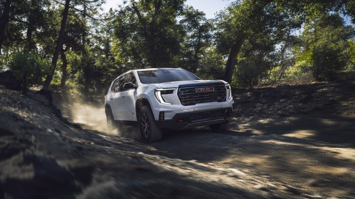 Le GMC Acadia qui roule en forêt dans un chemin boueux.