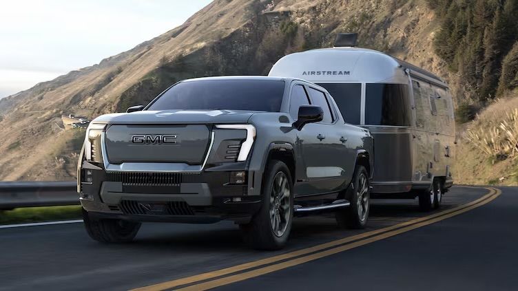 Le GMC Sierra EV Denali 2025 qui tire une roulotte Airstream dans un montée.