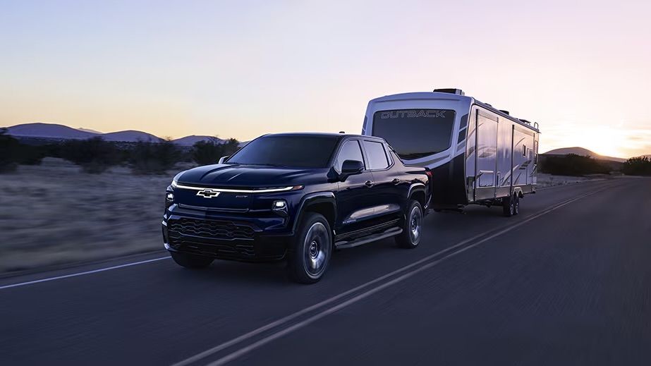 Le Chevrolet Silverado EV 2025 qui tire une grosse roulotte à la tombé de la nuit.