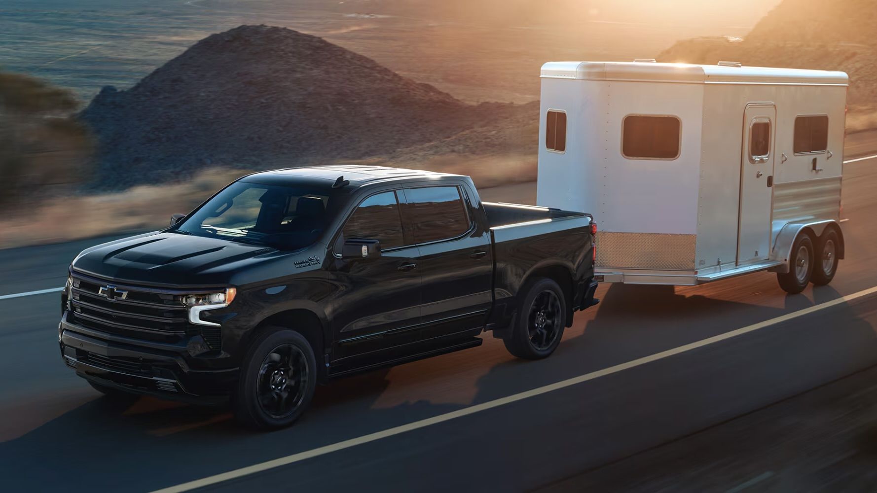 Le Chevrolet Silverado 1500 2025 qui tire une remorque à la tombé de la nuit.