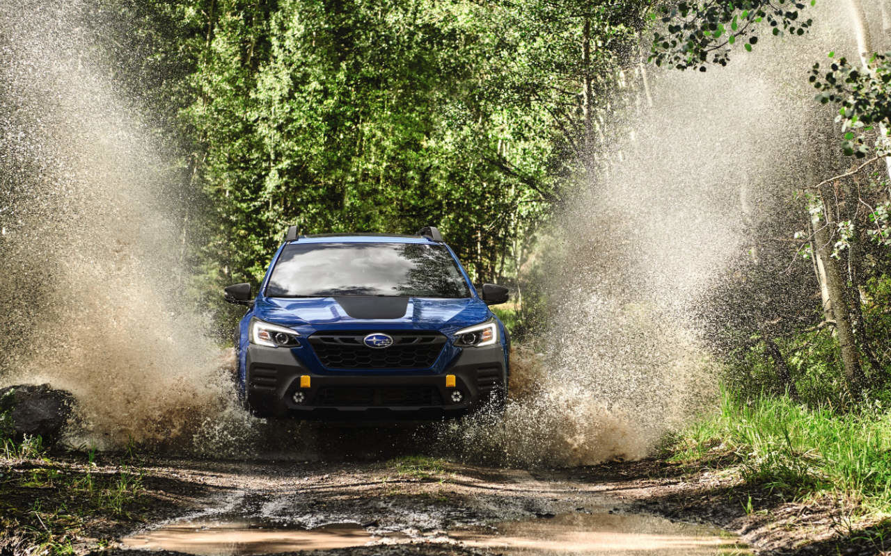 Vue avant du Subaru Outback 2023 éclaboussant de la l'eau dans la boue.