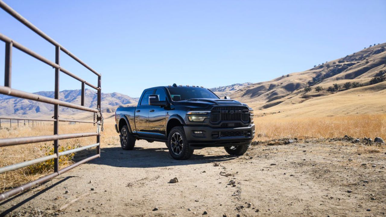 2026 Ram 2500 parked beside a ranch gate with dry hills in the background.
