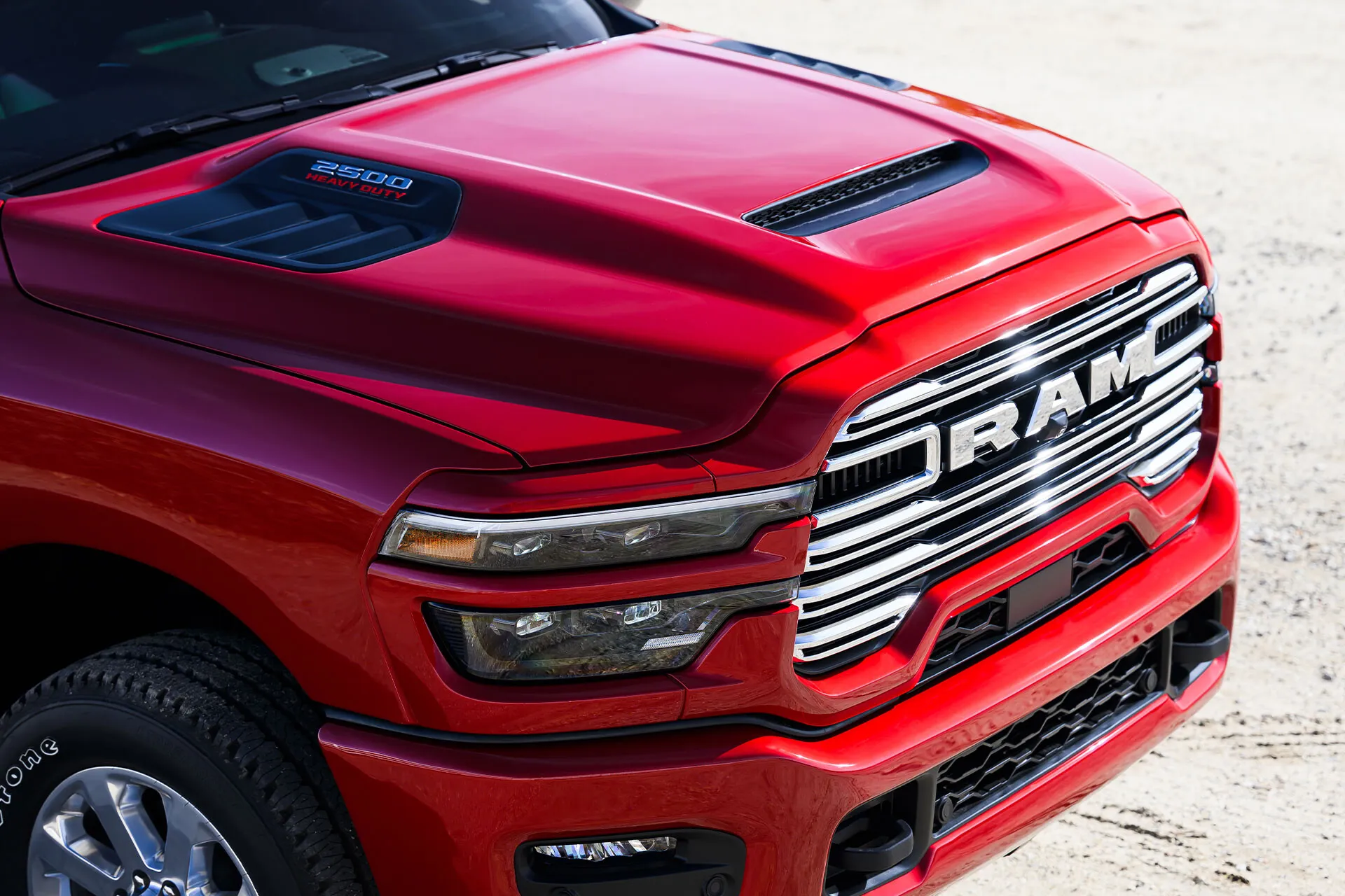 Close-up of the red 2027 Ram 2500 hood, chrome grille and headlights, with a 2500 Heavy Duty badge.