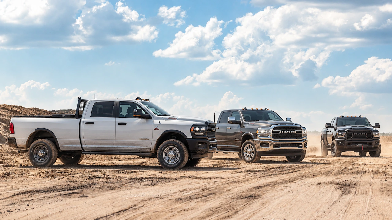 Three Ram 2500 pickups with different grille finishes and wheel designs on a sandy work site.