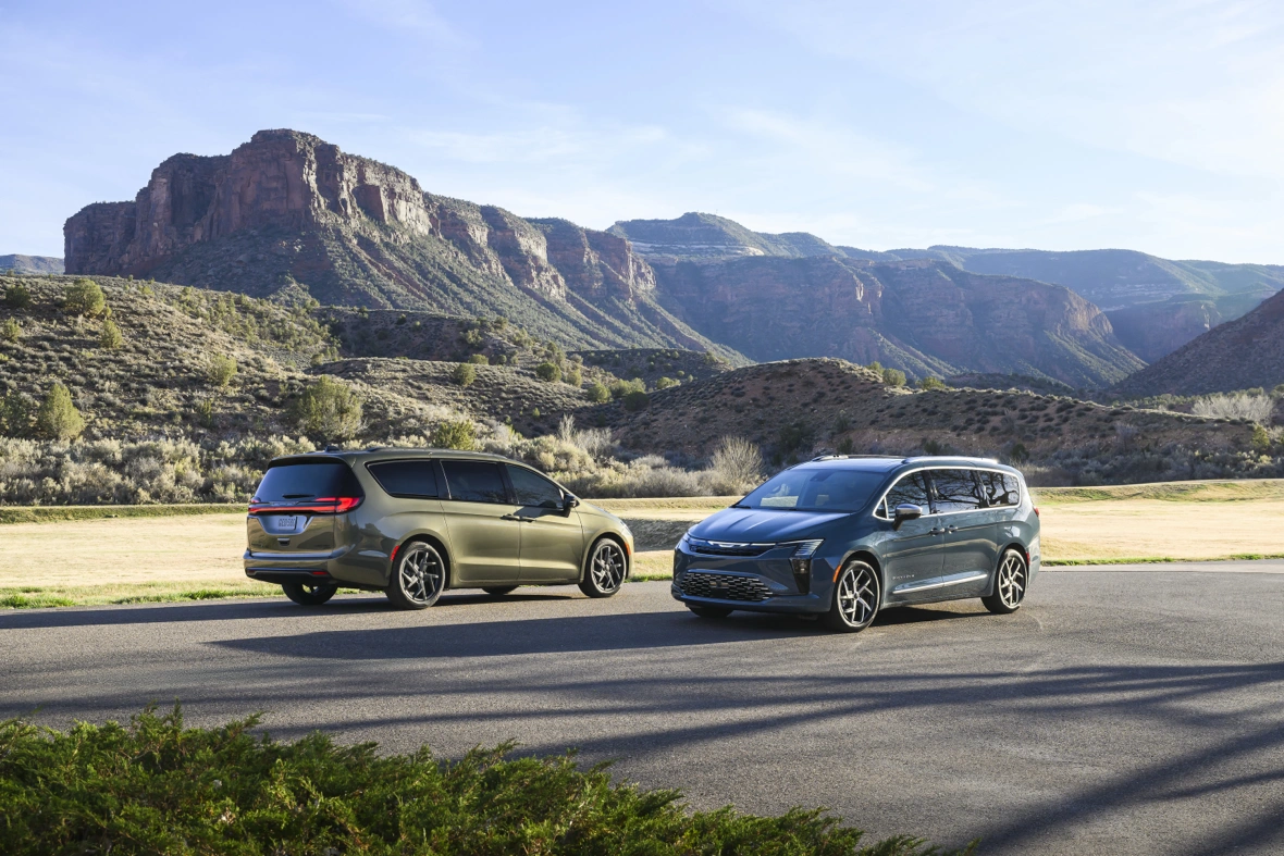 Two 2027 Chrysler Pacifica minivans shown from the front and rear three-quarter angles with mountains in the background.