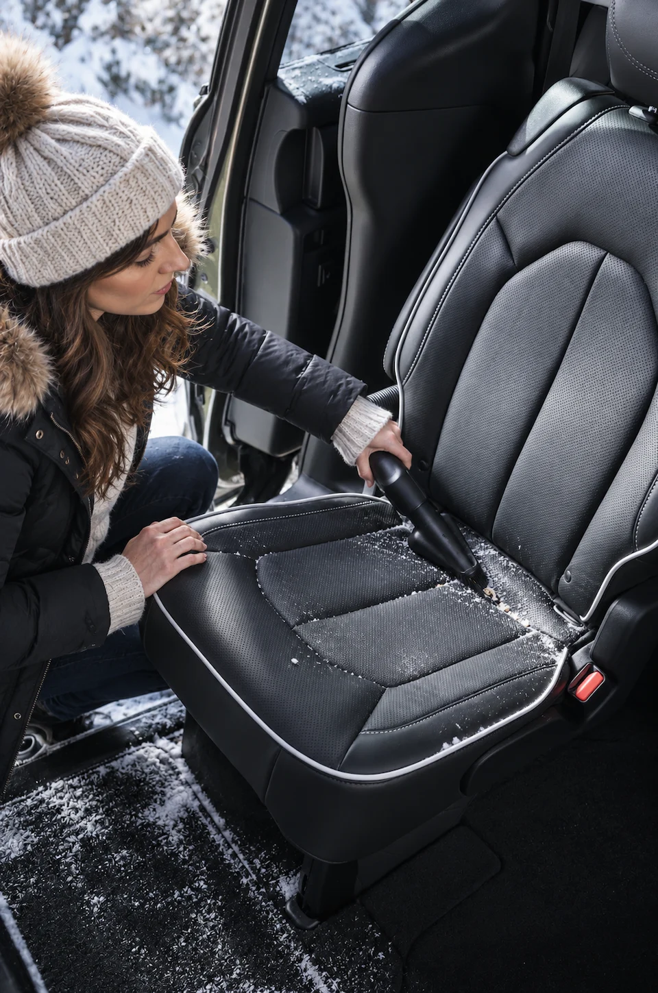 Person cleaning crumbs from a Chrysler Pacifica rear seat with the built-in Stow 'n Vac vacuum.