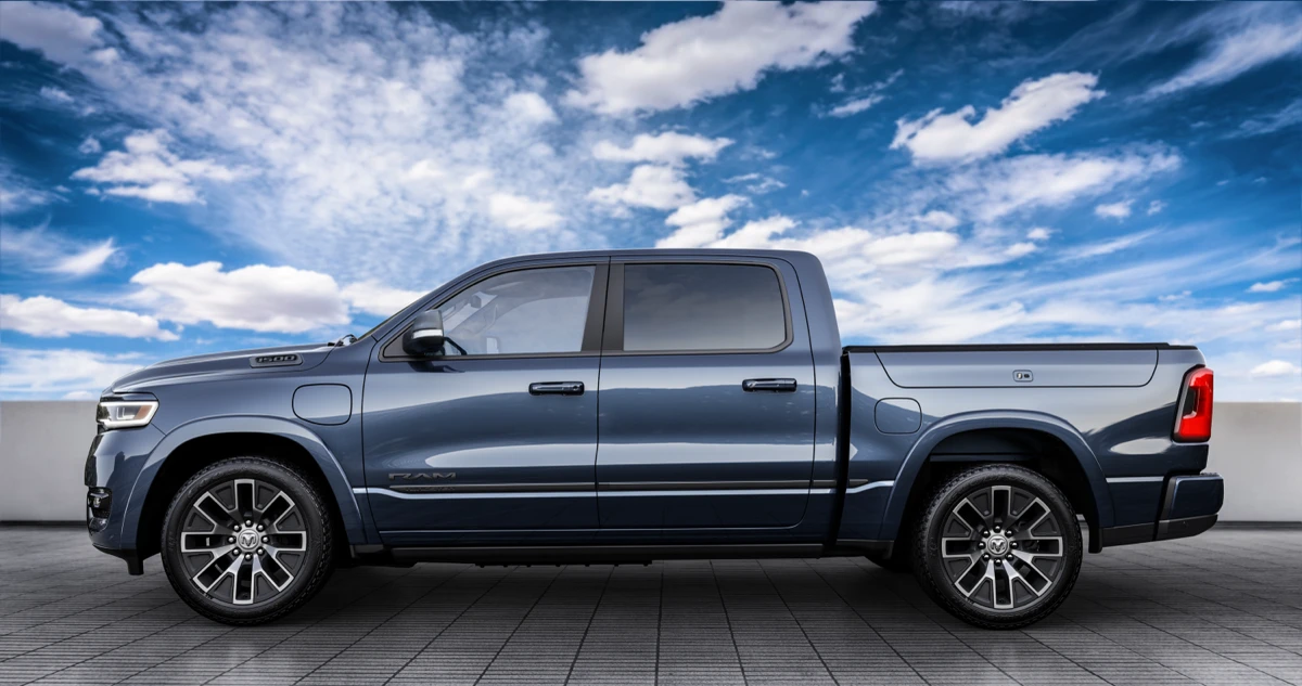 Blue Ram 1500 REV shown in profile with four doors, alloy wheels and a charging port on the front fender.