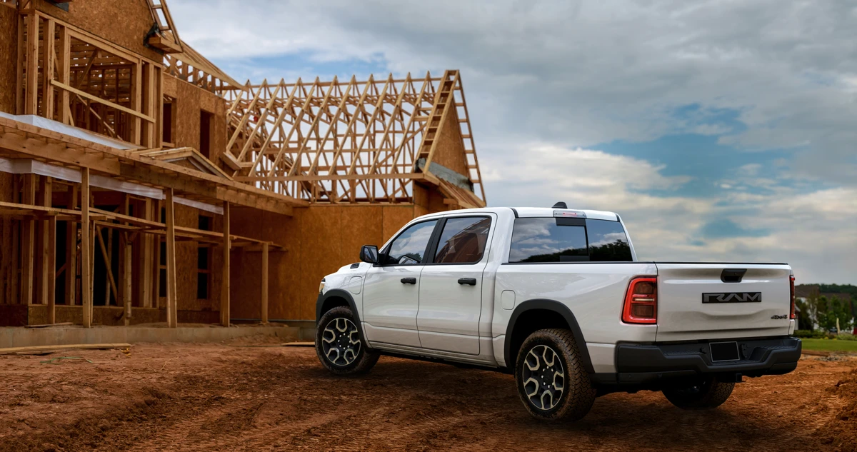 White Ram 1500 REV parked beside a house under construction, shown from the rear three-quarter angle.