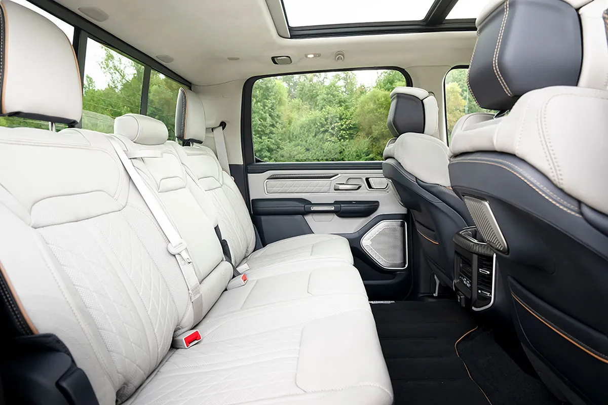 Ram 1500 REV Tungsten rear cabin with quilted light-coloured seats, decorative door trim and a panoramic sunroof.
