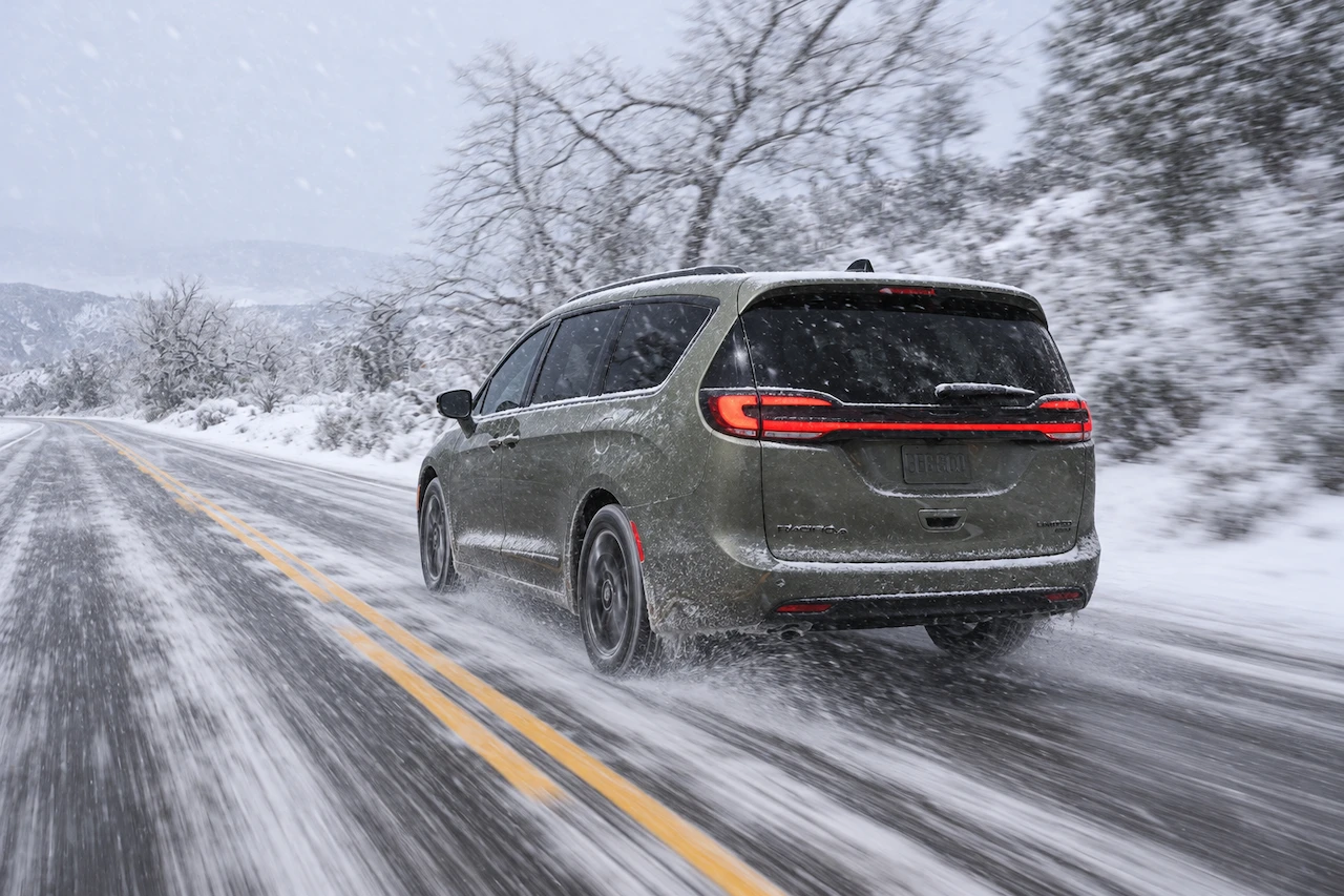 Chrysler Pacifica driving on a snow-covered road, illustrating winter conditions for the 2027 Select AWD.