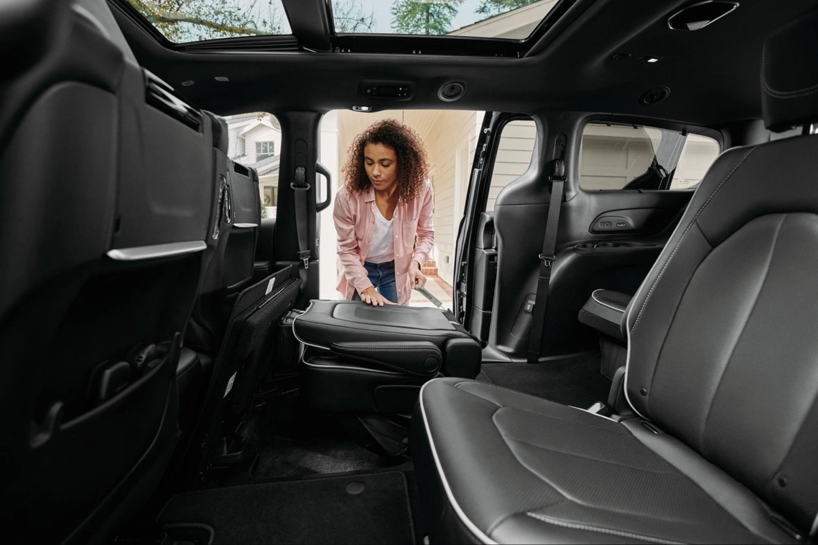 Woman adjusting a second-row seat inside a Chrysler Pacifica, showing its flexible passenger cabin.