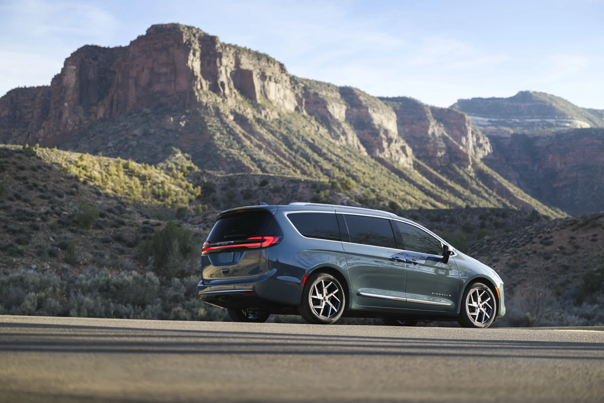 Rear three-quarter view of a grey 2027 Chrysler Pacifica parked beside a mountain road.