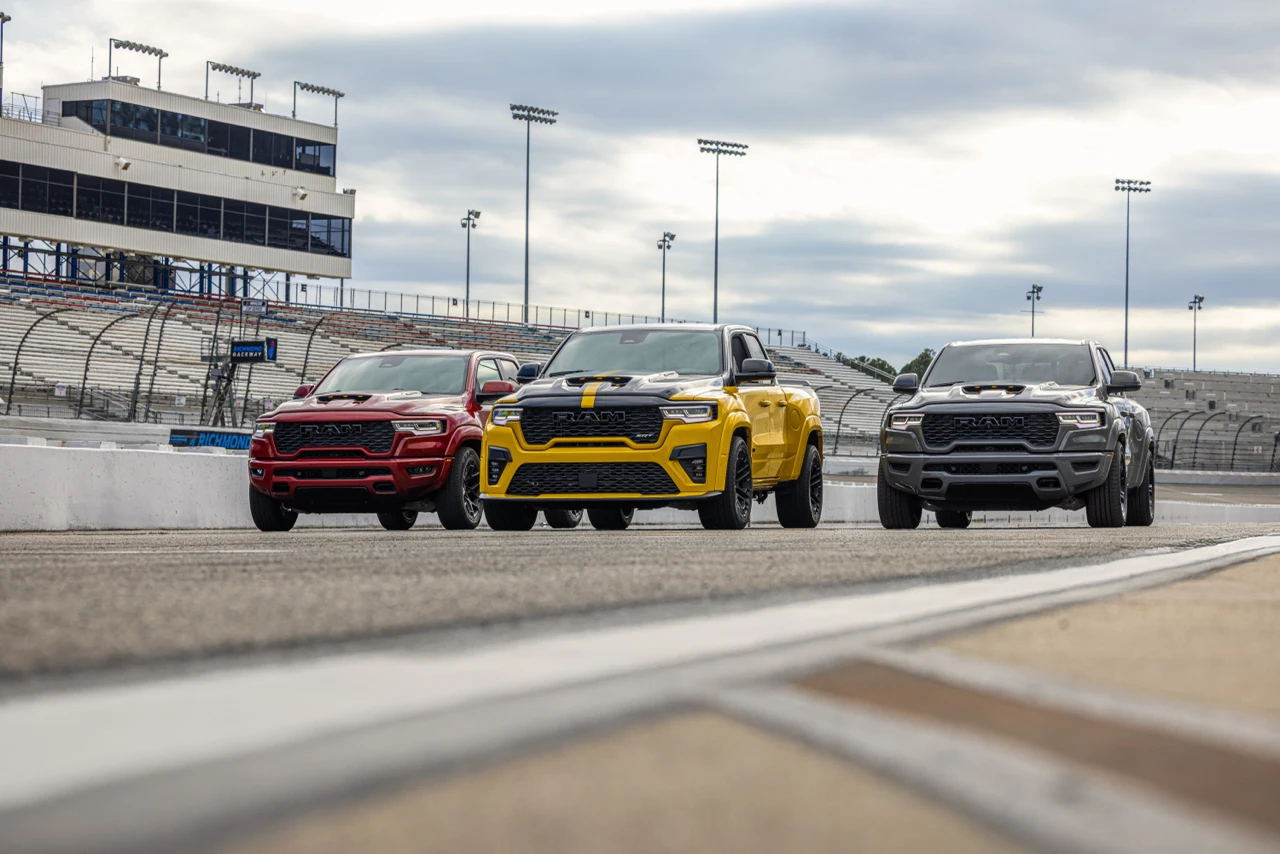 Red, yellow and grey 2027 Ram 1500 Rumble Bee pickup trucks lined up on a racetrack.