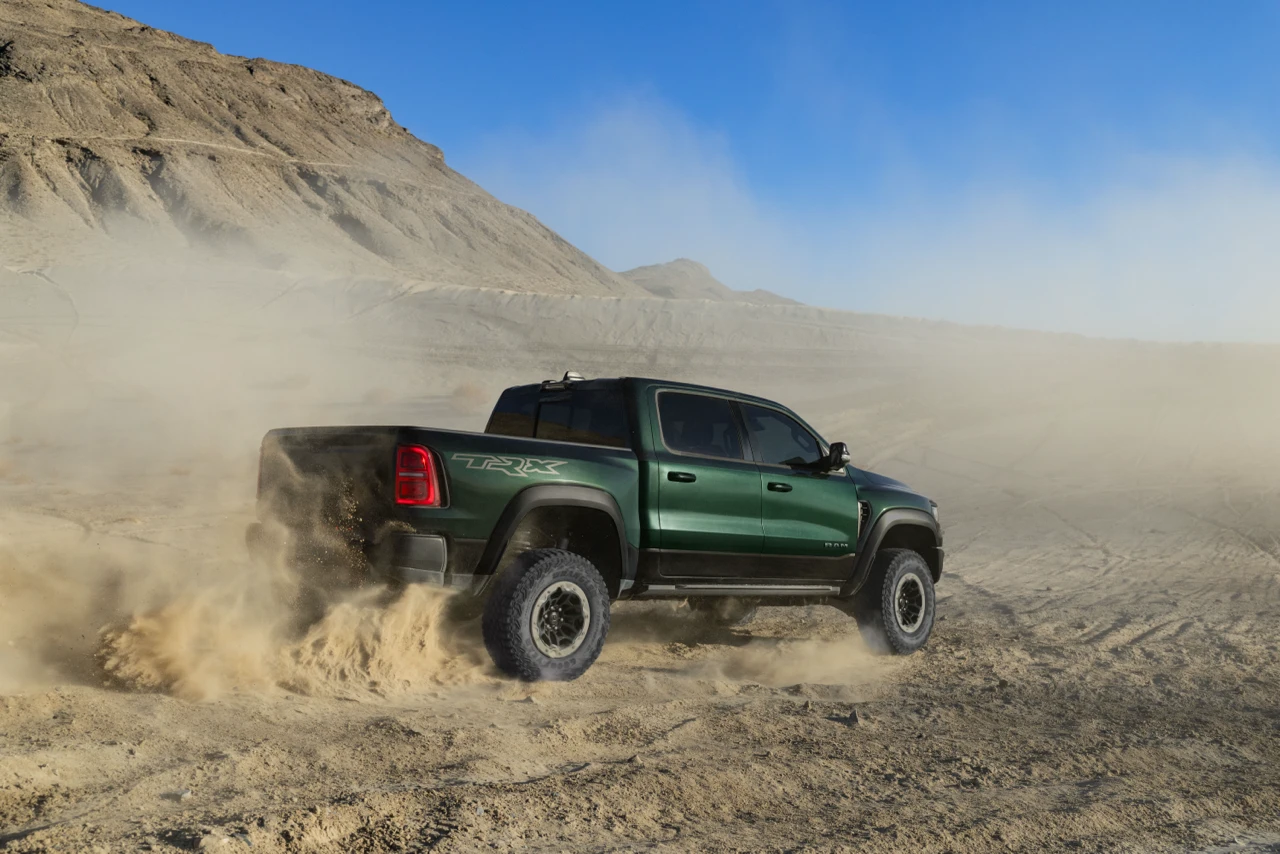 Green 2027 Ram 1500 RHO driving across rocky desert terrain and kicking up dust.