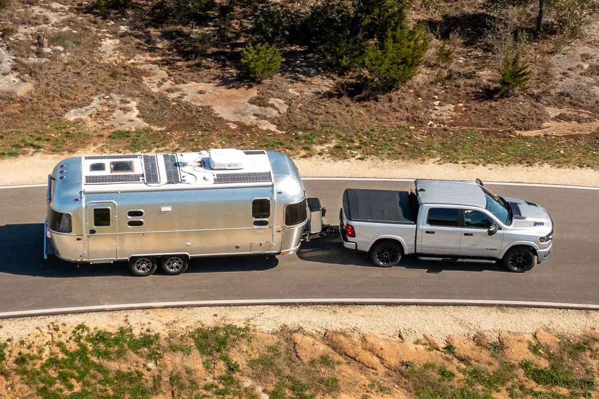 Overhead view of a Ram 1500 towing a travel trailer along a winding paved road.