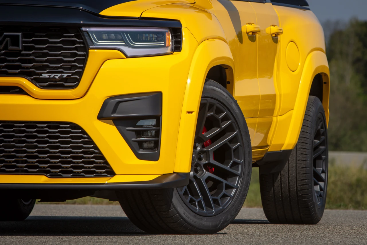 Close-up of the yellow 2027 Ram 1500 Rumble Bee front end, black grille and alloy wheel.