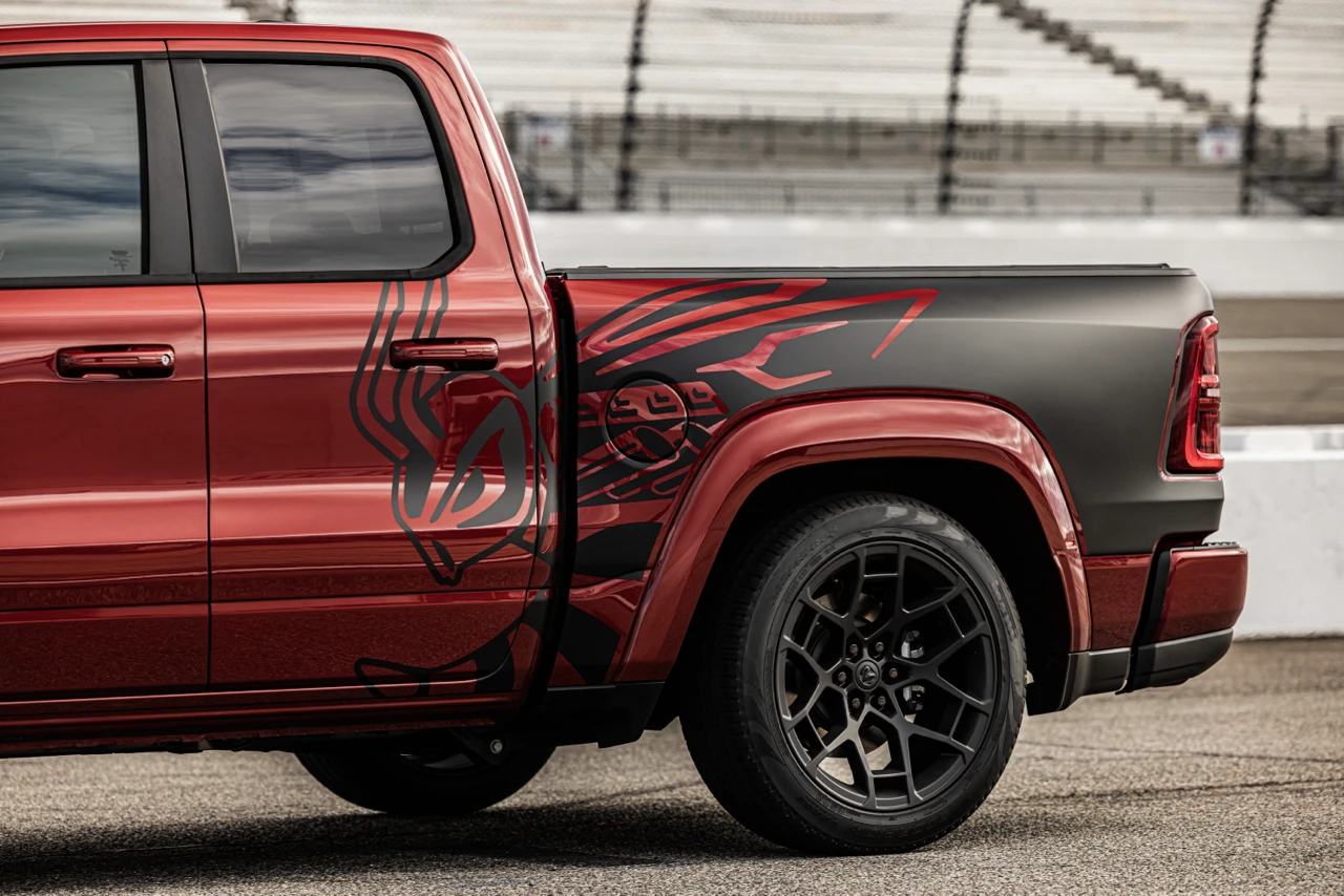 Red 2027 Ram 1500 Rumble Bee showing its short bed, black bee graphic and rear alloy wheel.