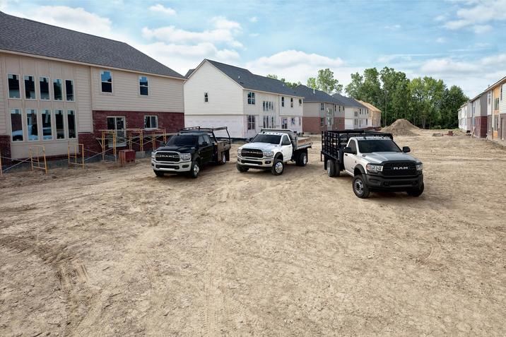Three RAM trucks parked at a construction site.