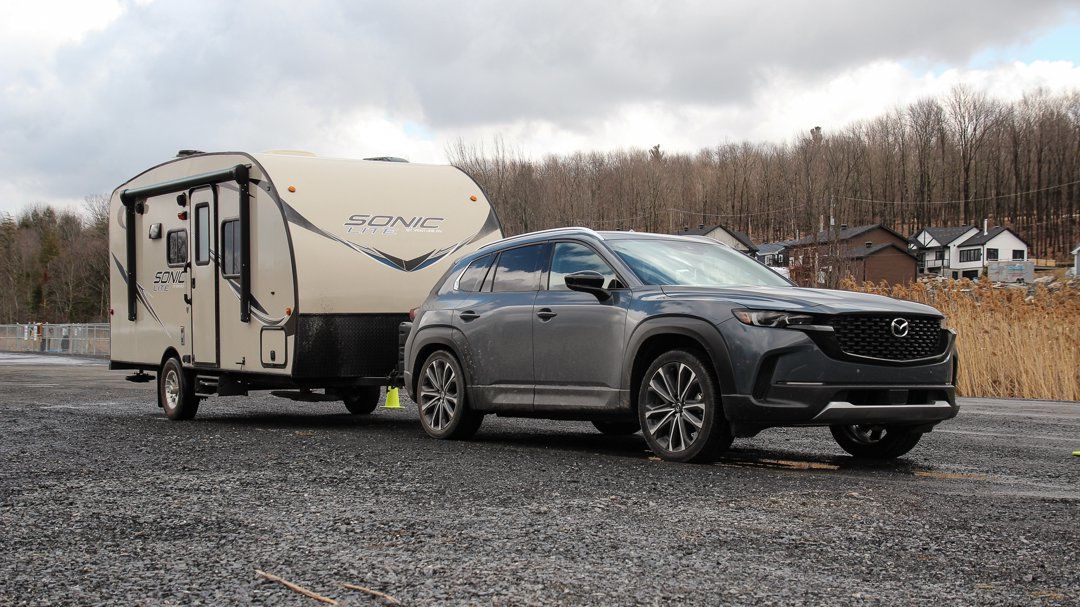 A 2023 Mazda CX-50 pulling a small trailer on a gravel road.
