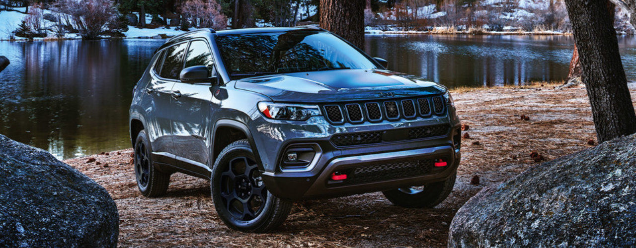 front side view of a 2024 Jeep Compass near a pond in a forest