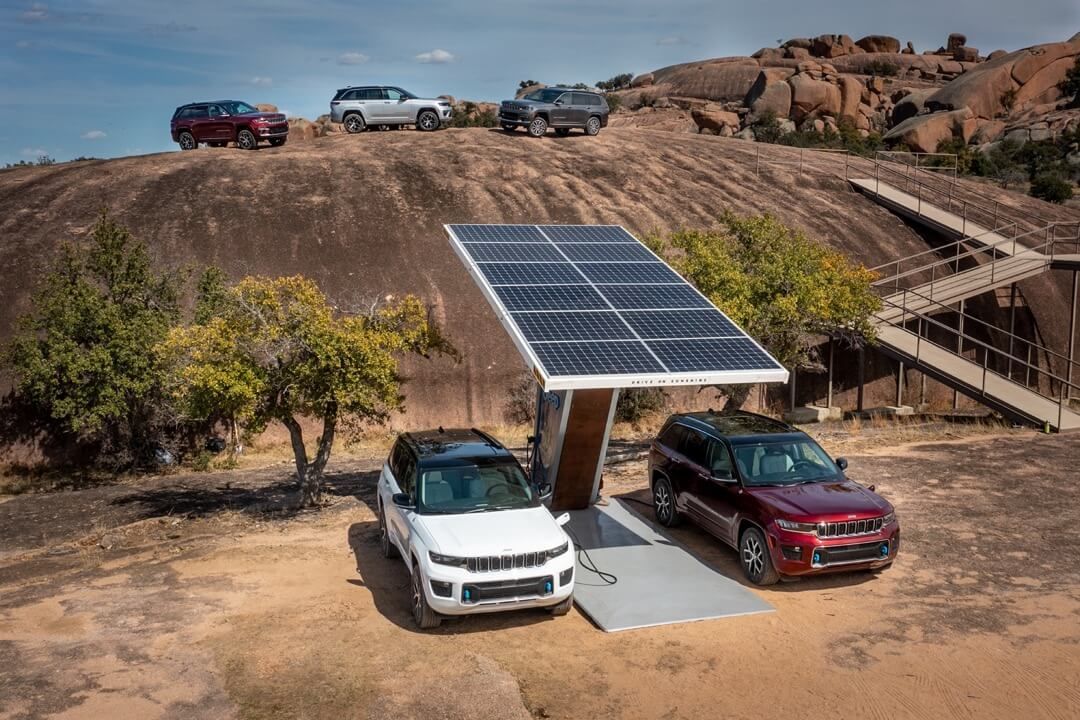vue d'une selection de Jeep Grand Cherokee 4xe en nature dont deux branchés à une station de recharge solaire