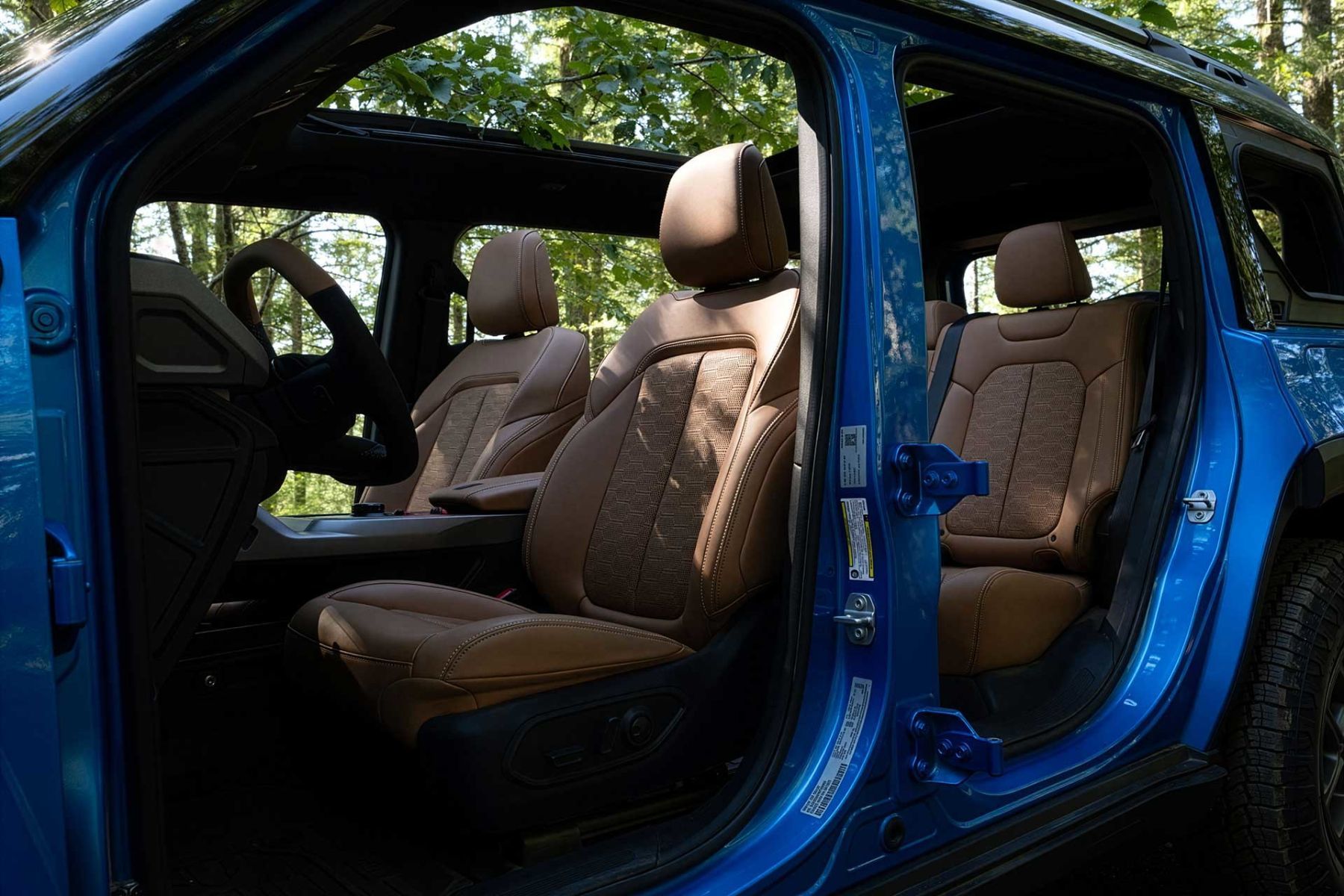 Habitacle du Jeep Recon 2026 bleu avec si&egrave;ges avant visibles et porti&egrave;res ouvertes.
