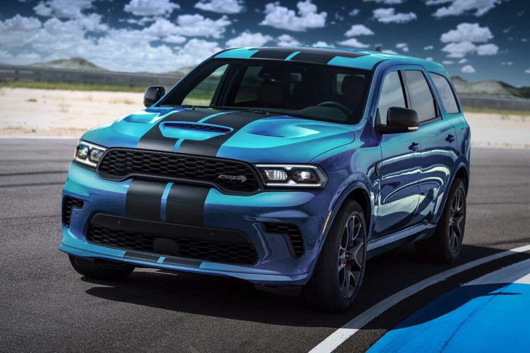 Blue Dodge Durango with 2 black stripes on the hood parked in a racetrack curve.