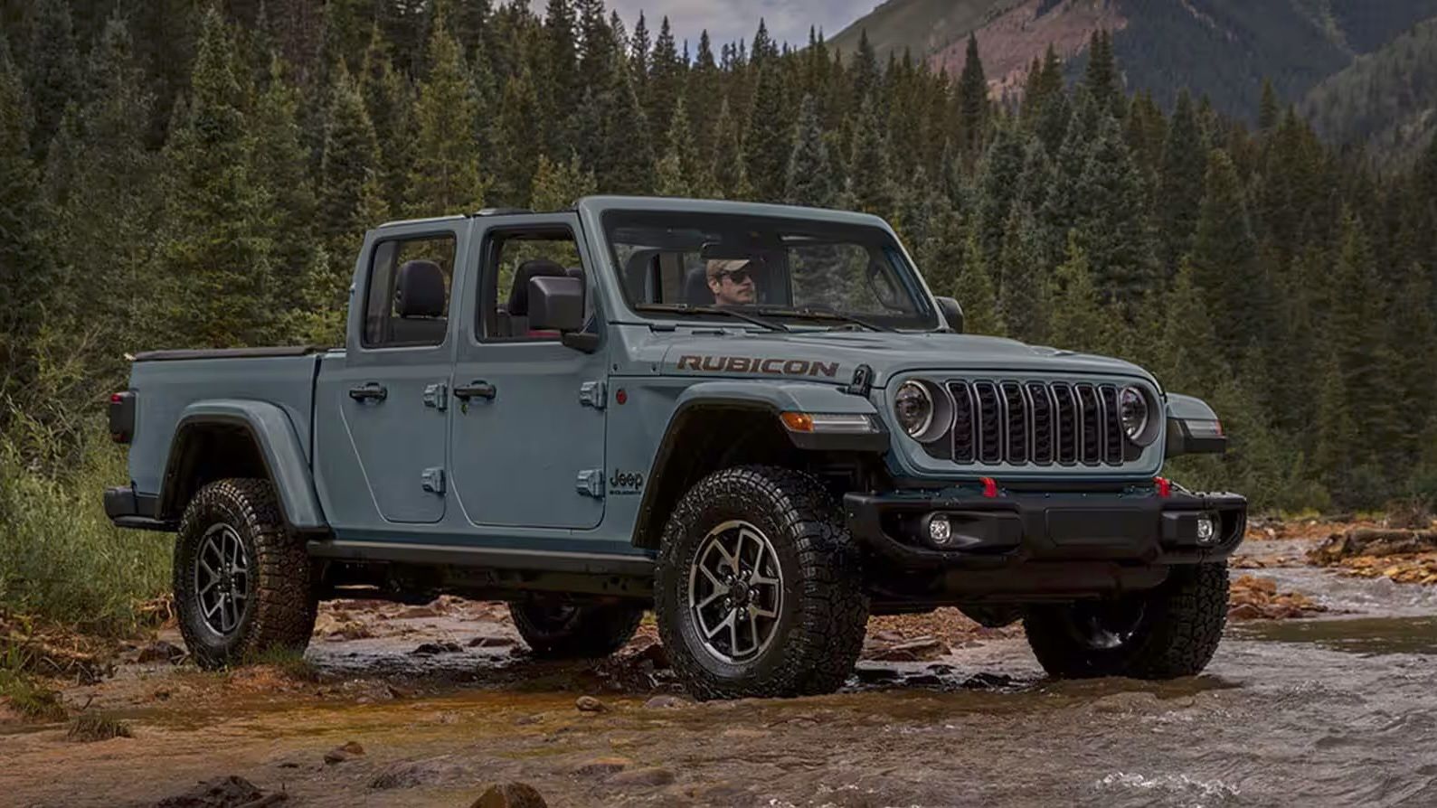 The Jeep Gladiator parked in the middle of a small river for a photo shoot.