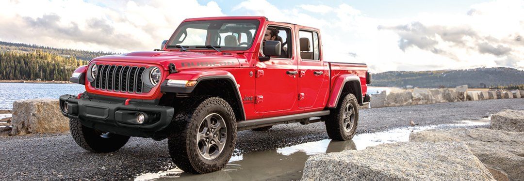 Un Jeep Gladiator roulant sur un chemin de gravel après la pluie.